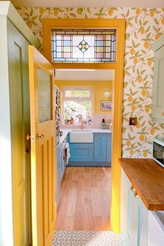 an open door leading to a kitchen with blue cabinets and yellow accents on the walls