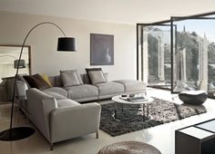 a living room filled with lots of furniture next to a large glass wall window that looks out onto the outdoors