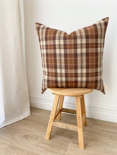 a brown plaid pillow sitting on top of a wooden stool