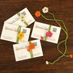 four cards with flowers on them are tied to string and placed on a wooden table