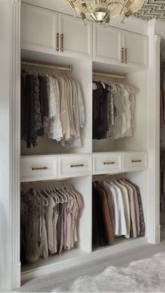 an organized closet with clothes hanging on the shelves and chandelier in the corner