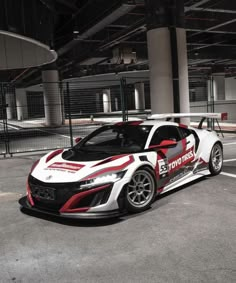 a white and red sports car parked in an empty parking lot next to a building