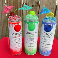 three cans of ciroc vodka on a table with umbrellas and strawberries