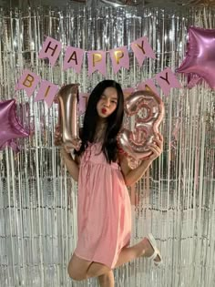 a woman posing with balloons in front of a happy birthday sign