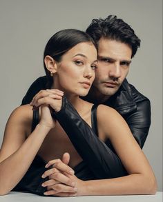 a man and woman are posing for a photo shoot in black leather outfits with their arms around each other