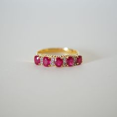 This fine vintage classic ring is most suitable for woman who loves vivid red African rubies. The ring is decorated by the 5 wonderful 0.95 total carat weight oval cut natural red ruby as the main stone and 8 round and natural 0.12 carats diamonds supports the beautiful red stones in between. A perfect every day ring for show off also especially for those passionate woman who were born in July. The ring is marked 750 for 18K solid yellow gold. Product Details: Metal: 18k Solid Gold Metal Color: Classic Red Oval Diamond Ring, Classic Ruby Diamond Ring, Classic Rings With Lab-created Ruby And Accent Stones, Red Oval Cluster Ring With Rose Cut Diamonds, Classic Red Round Band Rings, Classic Ring With Prong-set Lab-created Ruby, Classic Red Ruby Diamond Ring, Classic Red Diamond Cluster Ring, Vintage Diamond Ruby Ring