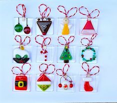 twelve christmas ornaments are hanging from red and green ribbons on clear acrylic tags