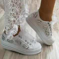 a close up of a person's shoes with white lace and flowers on them