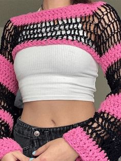 a close up of a person wearing a pink and black knitted sweater with long sleeves