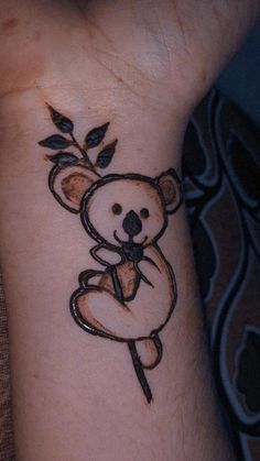 a tattoo on the wrist of a person with a teddy bear holding a plant in it's paws