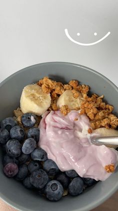 a bowl filled with blueberries, bananas and granola next to a cup of yogurt