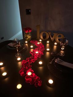 a table with candles and flowers on it that spell out the word love next to some wine glasses