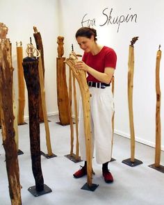 a woman standing in front of wooden sculptures