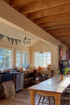 an open kitchen and dining room with wood flooring, white walls and wooden ceiling