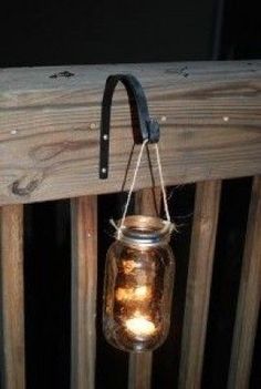 a lantern hanging from the side of a wooden fence with two candles in it,