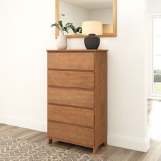 an empty room with a dresser, mirror and vase on the floor in front of it