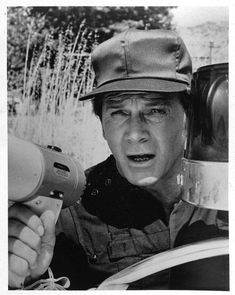 black and white photograph of a man holding a hair dryer in front of his face