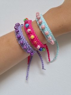 three bracelets with beads are on someone's arm, one is pink and the other is blue