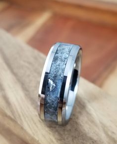 a wedding band with an antler wood inlay is shown on a wooden surface