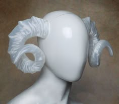 a white mannequin head with large horns on it's back and sides