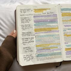 someone is holding an open bible with colorful writing on the pages and in front of them