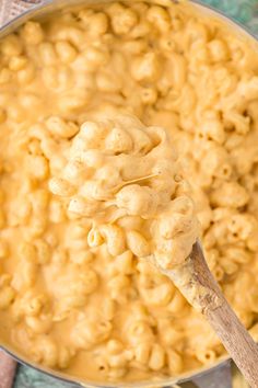 a wooden spoon full of macaroni and cheese on top of a blue cloth