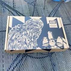 a box with an image of a bear and two birds on it sitting on a mesh surface