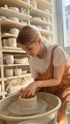 a woman is making a pot on a potter's wheel