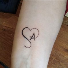 a small heart tattoo with the letter s in it's center on someones arm