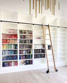 a ladder leaning against a bookshelf in a room with white walls and wooden floors