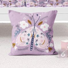 a purple pillow sitting on top of a bed next to a pink toy box and other items