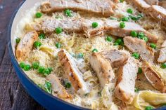 pasta with chicken, peas and parmesan cheese in a blue bowl on a wooden table