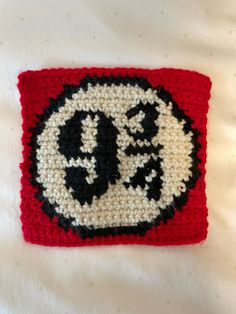 a crocheted square with the letter o in black, white and red colors