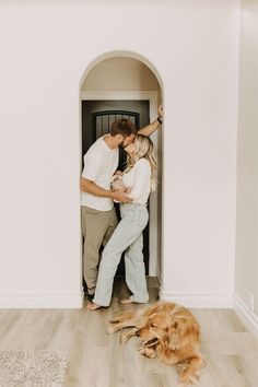 a man and woman standing in front of a doorway with a dog laying on the floor