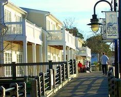 people are walking down the sidewalk in front of some white buildings with balconies