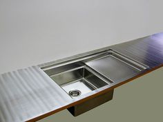 a stainless steel sink on top of a wooden table in a room with white walls