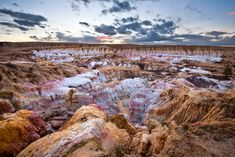 the sun is setting over an area with many colored rocks and trees in it,