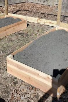 three wooden raised beds with gravel in them