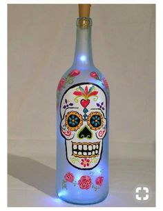 a light up bottle with a skull painted on the side and flowers all over it