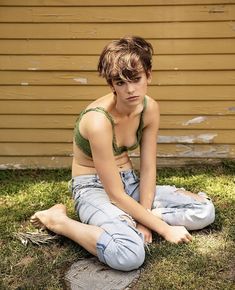 a young woman sitting on the grass in front of a house