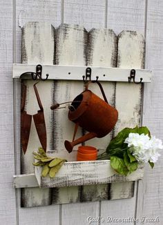 an old window frame is decorated with garden tools and potting implements as well as flowers