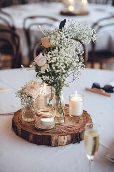 a table with candles, flowers and jars on it is set up for a wedding reception