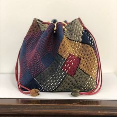 a small purse is on display in a glass case with a wooden frame and white wall behind it