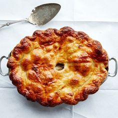 a pie sitting on top of a table next to a fork and knife with a spoon in it