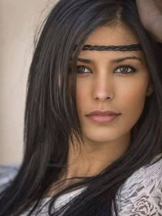 a woman with long black hair is posing for the camera and has her hand on her head