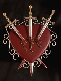 a red heart with two swords attached to it and some other items in the shape of a heart