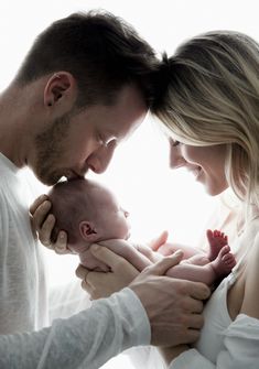 a man and woman holding a baby in their arms