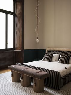 a large bed sitting next to a window on top of a white rug in a bedroom