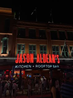 the neon sign for jason alden's kitchen and rooftop bar is lit up at night