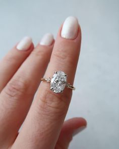 a close up of a person's hand with a diamond ring on their finger